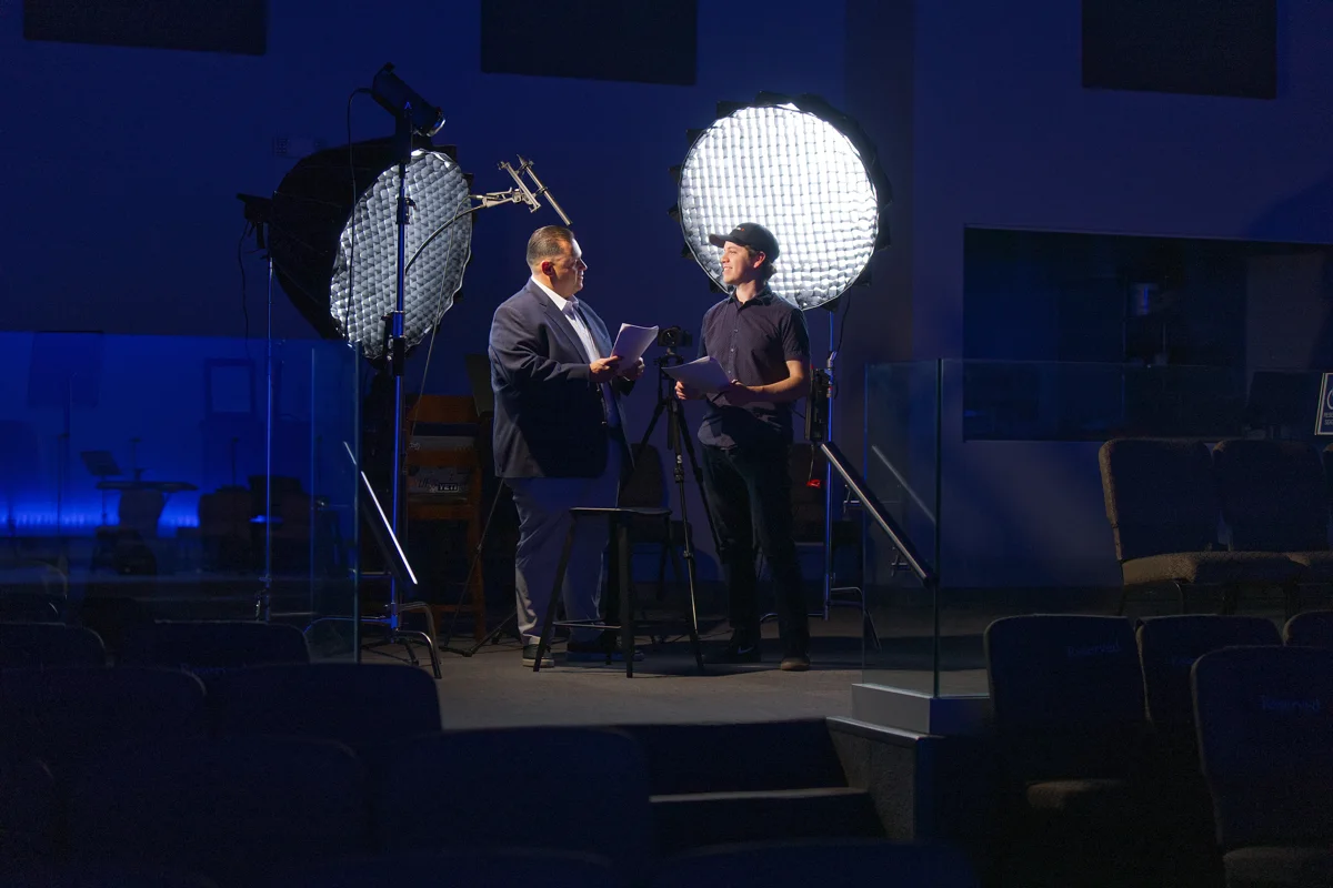 Dan guiding a client through a recording session with camera, lights, and microphone